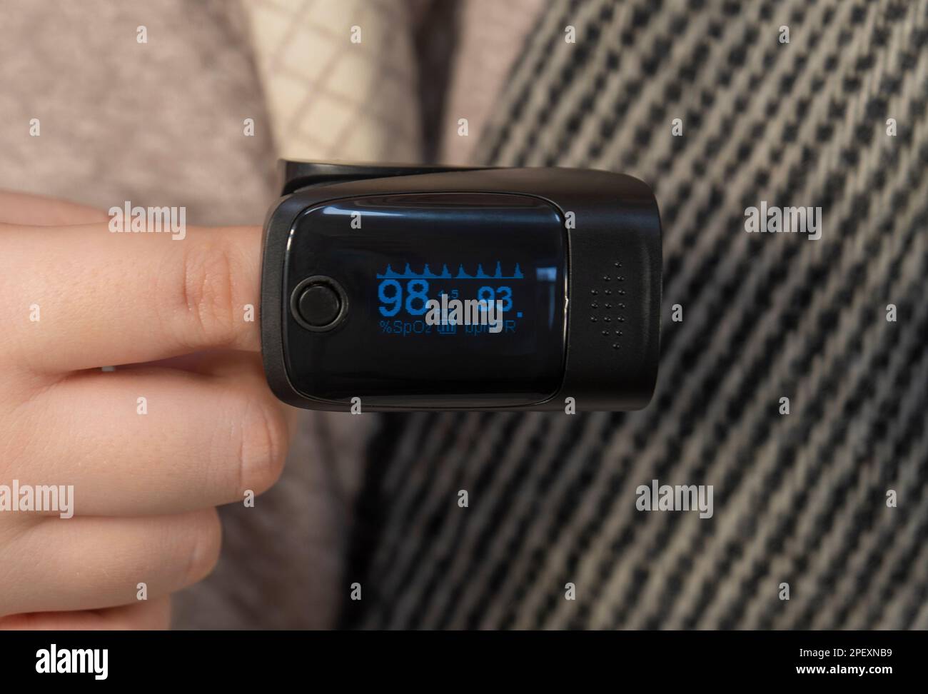 Oximeter is put on a finger (close-up). Measurement of the level of oxygen in the blood. Concept of medicine, healthcare, pharmacy and home treatment Stock Photo