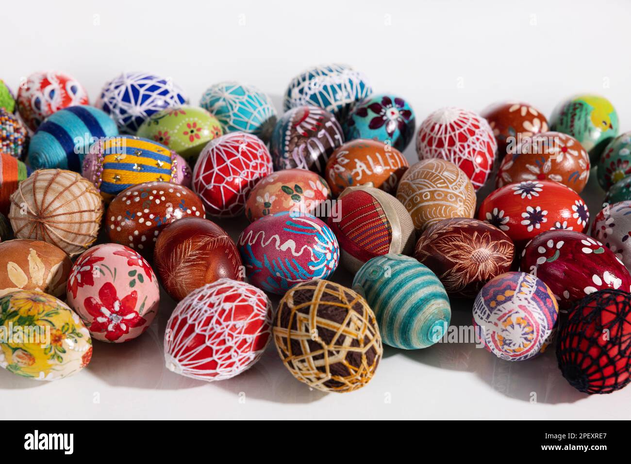 Many different colored Easter eggs lie side by side on a white background. Stock Photo