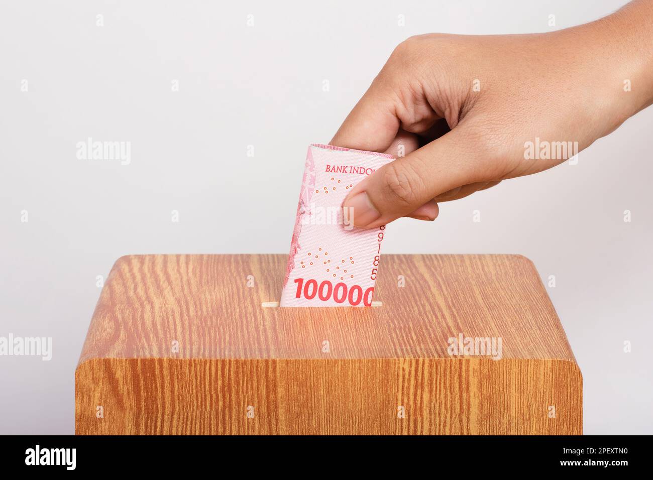 hand put indonesian rupiah money into the charity box as a donation. Help each other, alms concept. Stock Photo