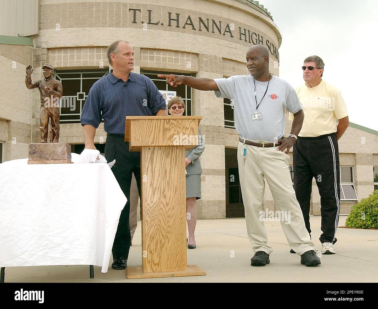 Former T.L. Hanna High School football coach, Harold Jones, right, watches  as James Robert "Radio" Kennedy, center, points to a small scale statue of  himself that was done by Andy Davis, left,