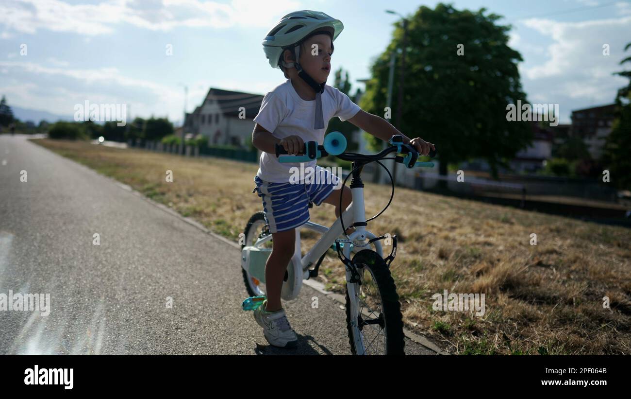 Active child learning to ride bike. Kid loses equilibrium balance while riding bicycle. Slow motion handheld footage Stock Photo