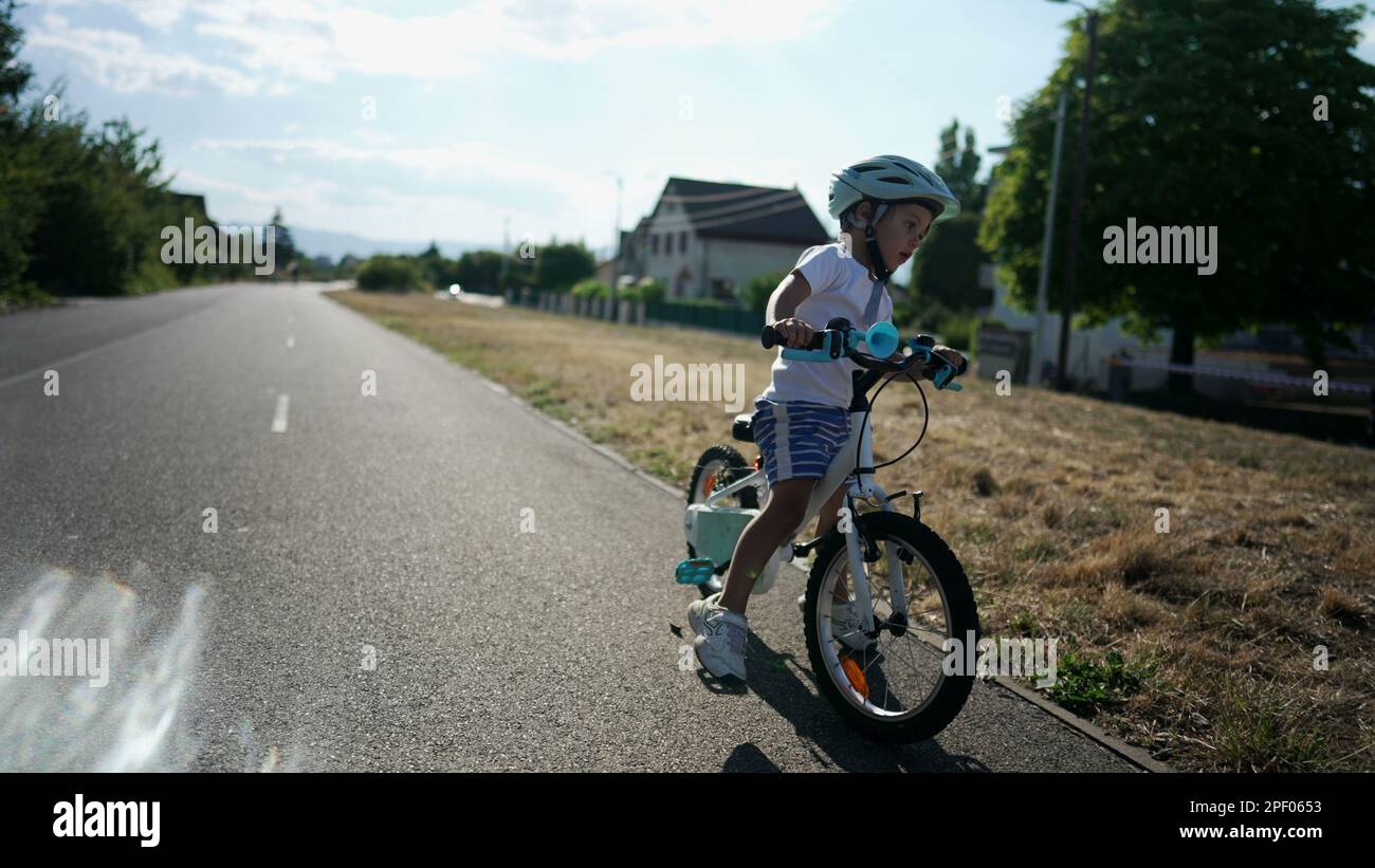 Active child learning to ride bike. Kid loses equilibrium balance while riding bicycle. Slow motion handheld footage Stock Photo