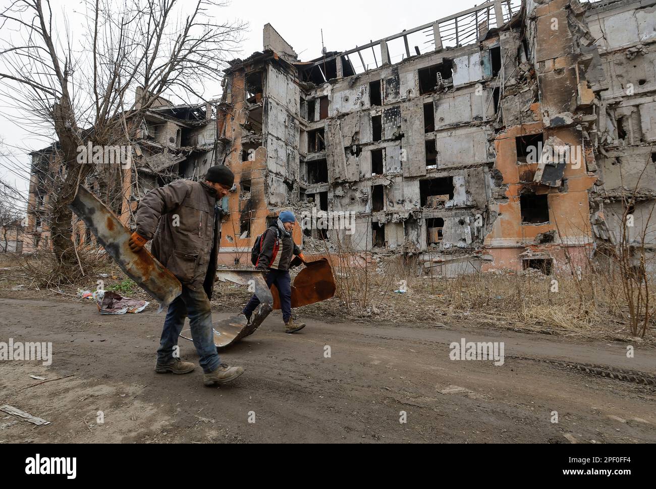 Local residents walk past a multi-storey apartment block, which was destroyed in the course of Russia-Ukraine conflict, in Mariupol, Russian-controlled Ukraine, March 16, 2023. REUTERS/Alexander Ermochenko Stock Photo