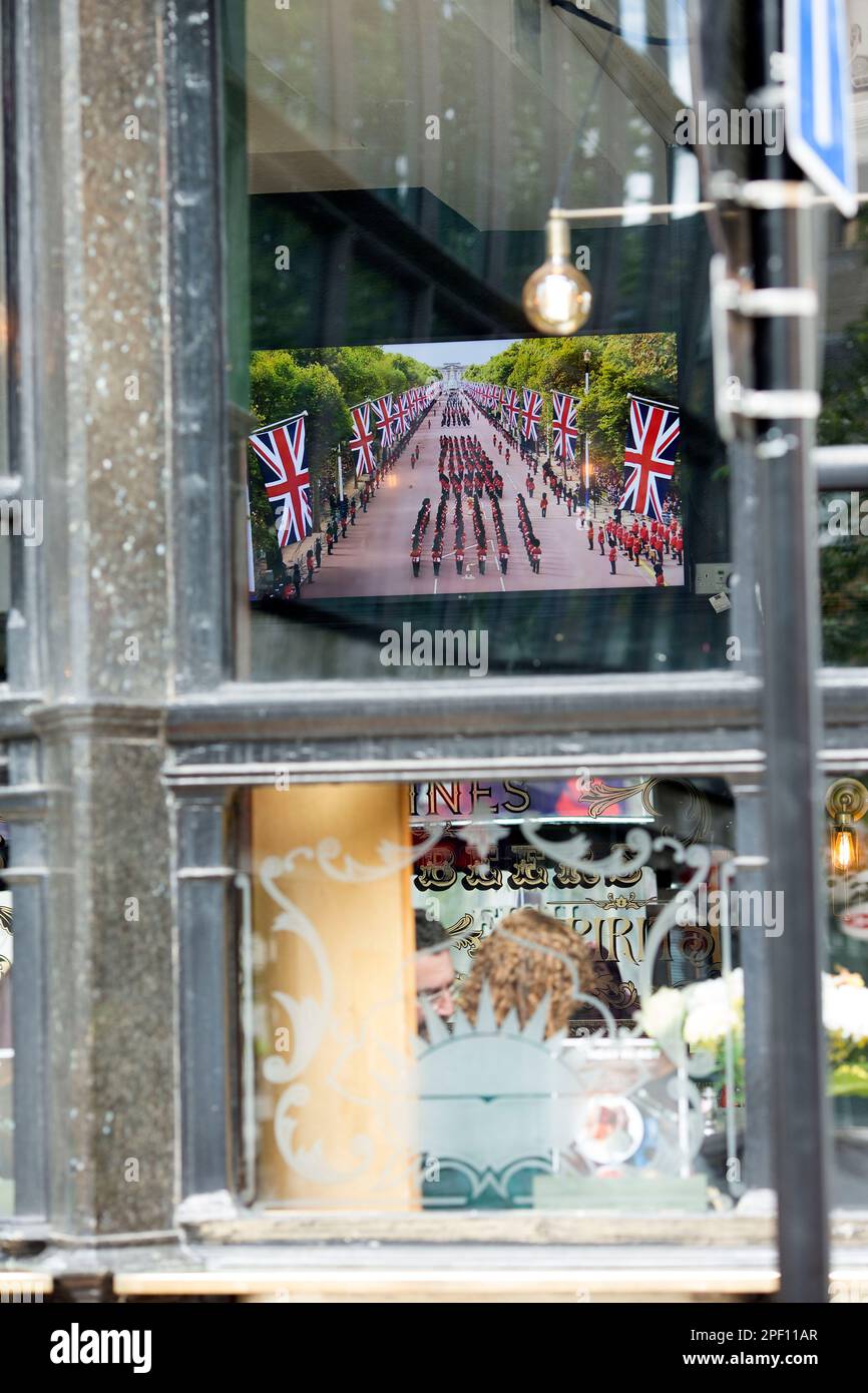 A TV screen displays the funeral day coverage of the late Queen