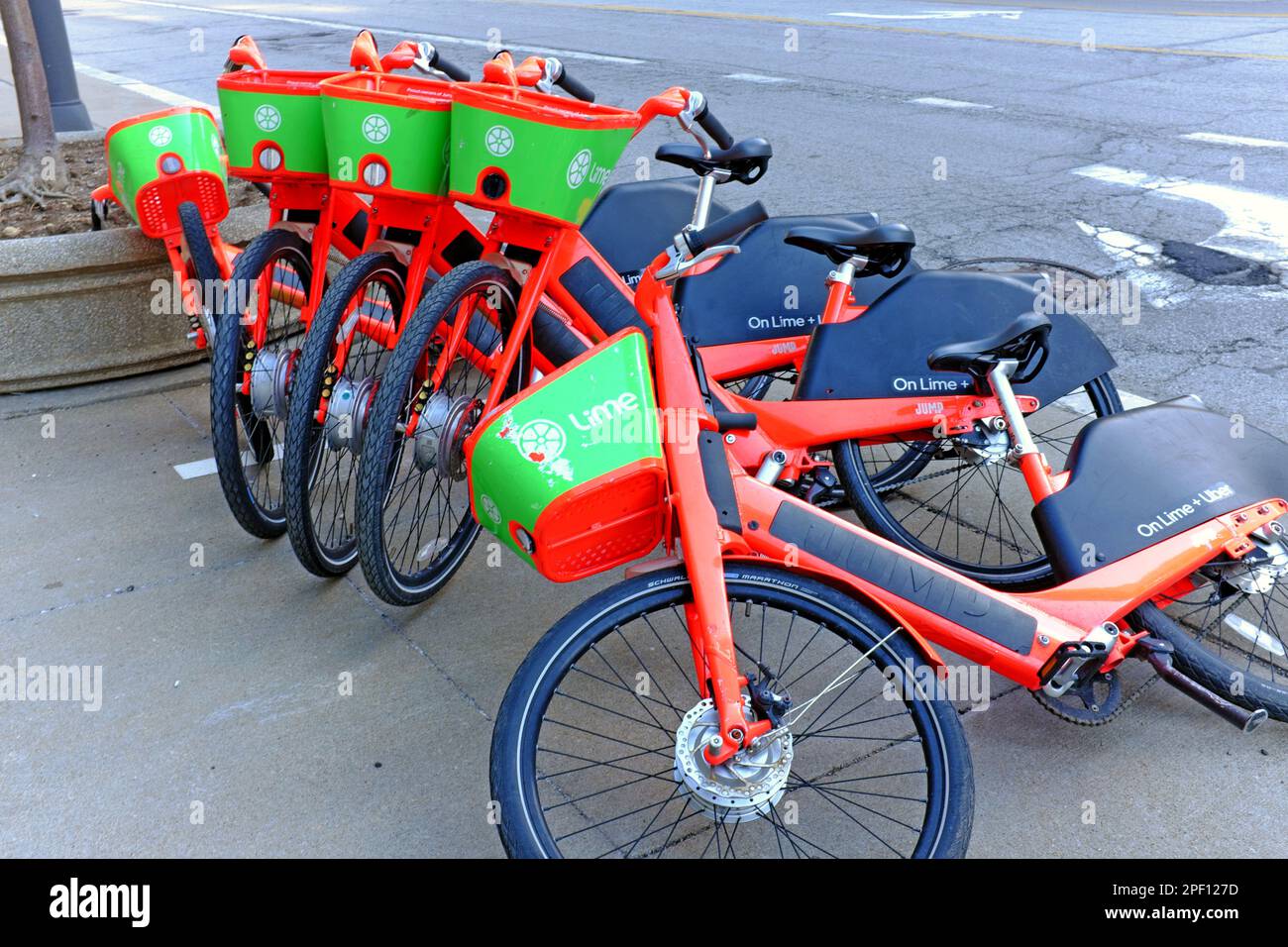 Green and orange Lime bicycles fallen over on a sidewalk in downtown Cleveland, Ohio, USA. Stock Photo