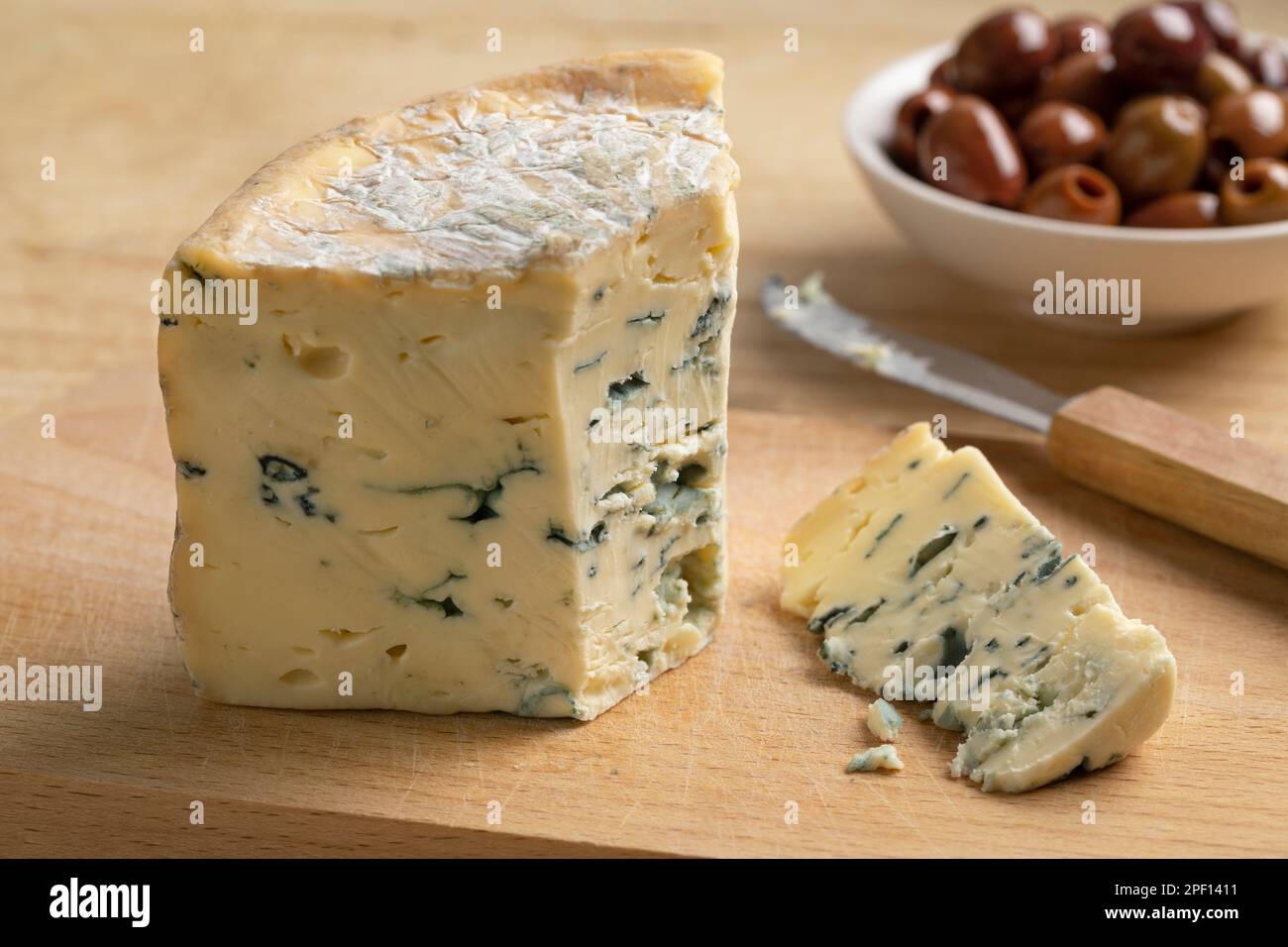 Piece of French blue Fourme d 'Ambert cheese and a on a cutting board for a snack close up Stock Photo