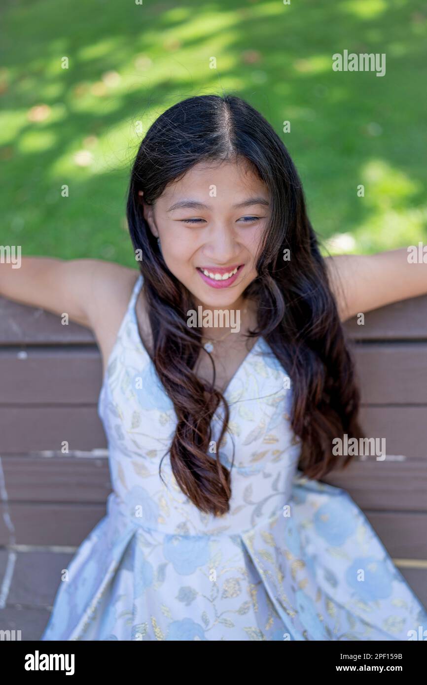 Beautiful Teenage Asian Girl Sitting on a Park Bench in Prom Dress | afternoon | happy | smile Stock Photo