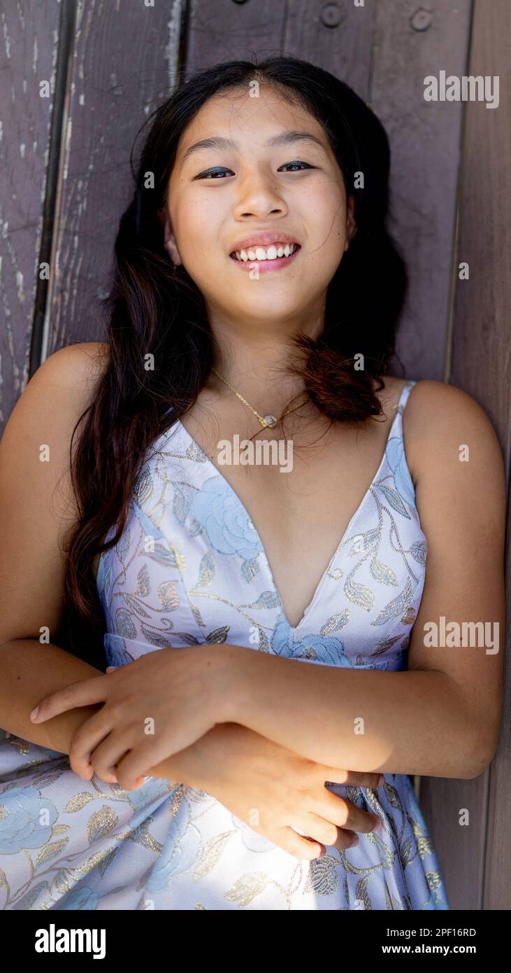 Beautiful Teenage Asian Girl Laying on a Park Bench Smiling Wearing Prom Dress Stock Photo
