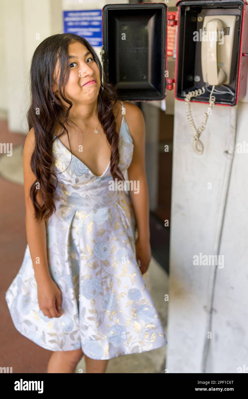 Teenage Asian Girl Looking at a Landline Phone and Looking Confused | Obsolete Technology | Reaction Stock Photo