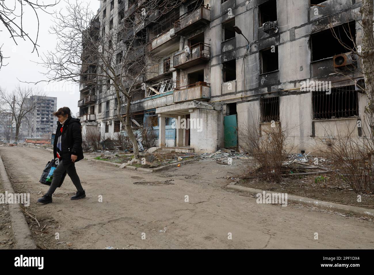A local resident walks outside a multi-storey apartment block, which was destroyed in the course of Russia-Ukraine conflict, in Mariupol, Russian-controlled Ukraine, March 16, 2023. REUTERS/Alexander Ermochenko Stock Photo