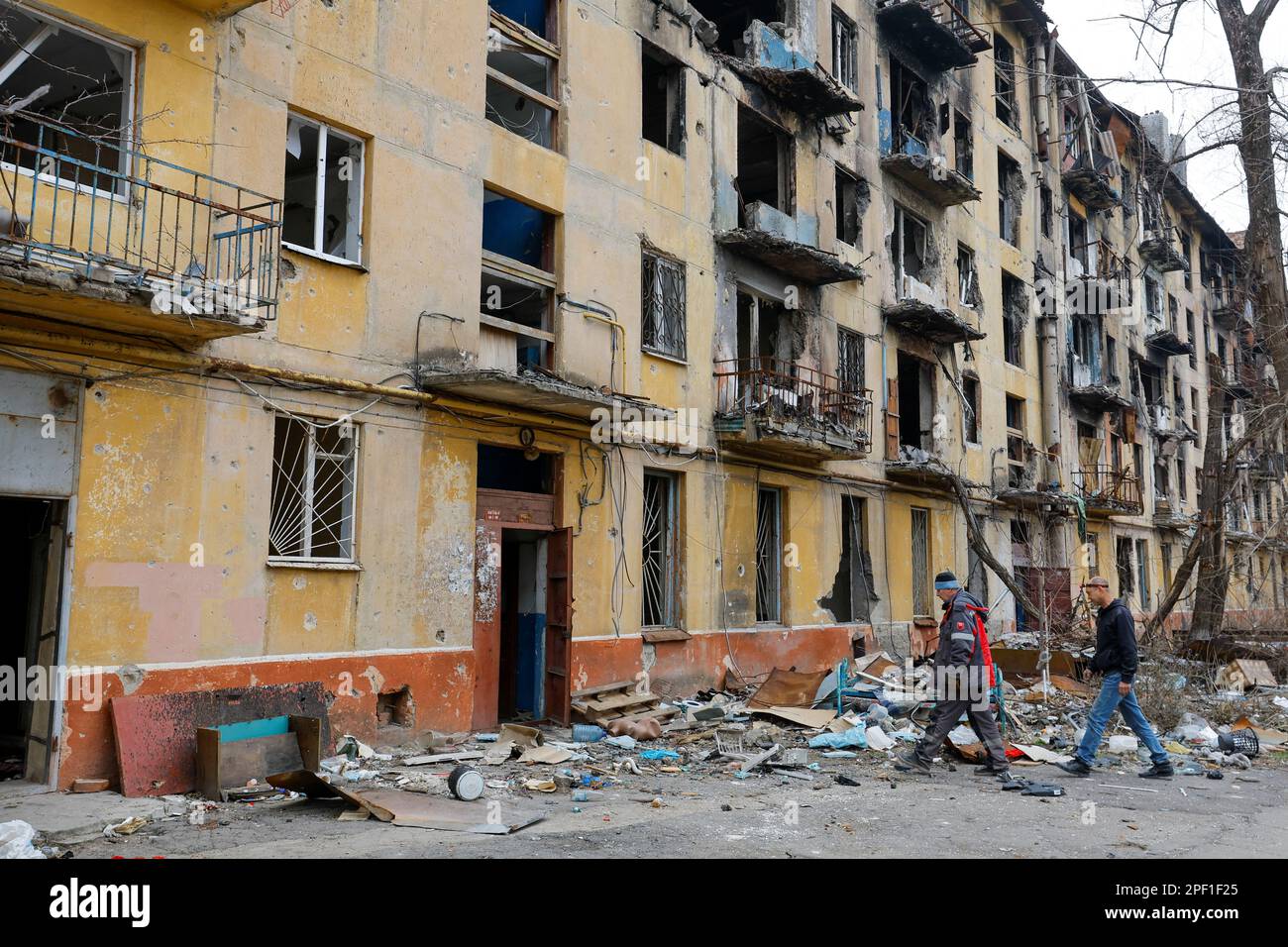 Men approach a multi-storey apartment block, which was destroyed in the course of Russia-Ukraine conflict, in Mariupol, Russian-controlled Ukraine, March 16, 2023. REUTERS/Alexander Ermochenko Stock Photo