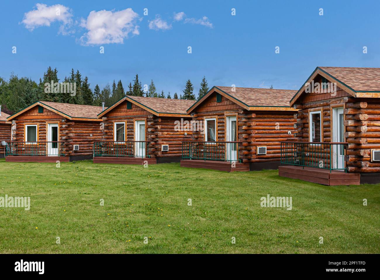 Fairbanks, Alaska, USA - July 27, 2011: Chena River and Pikes Waterfront Lodge offers brown wooden small dwellings behind green lawn under blue sky Stock Photo