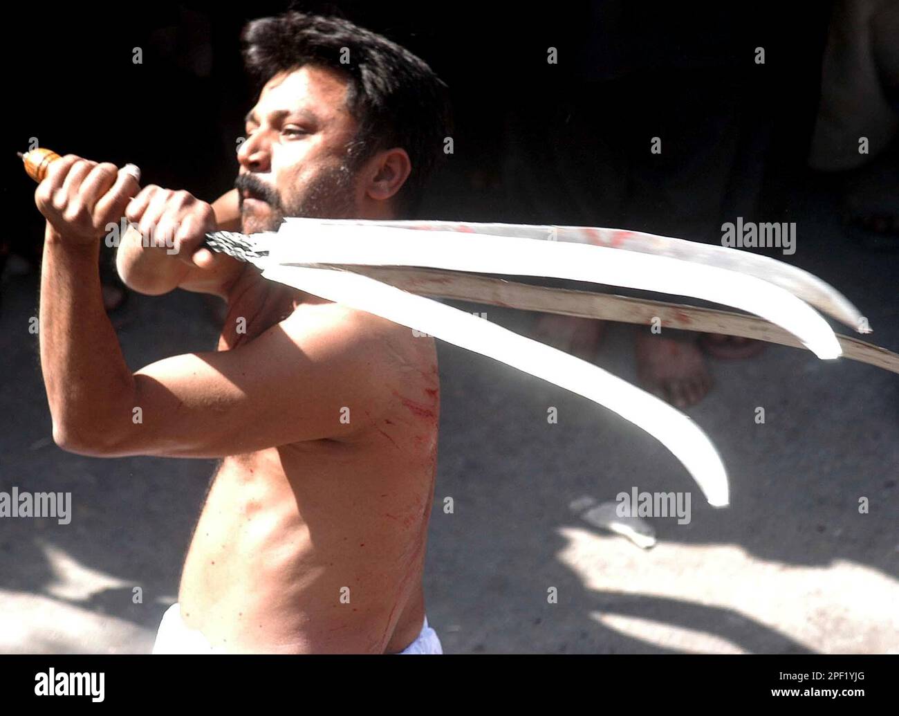 Shiite Muslim beats himself with knives in chain during a Muharram  procession in Lahore, Pakistan on Monday, March 1, 2004. Muharram is the  mourning month for Shiite Muslims in remembrance of the