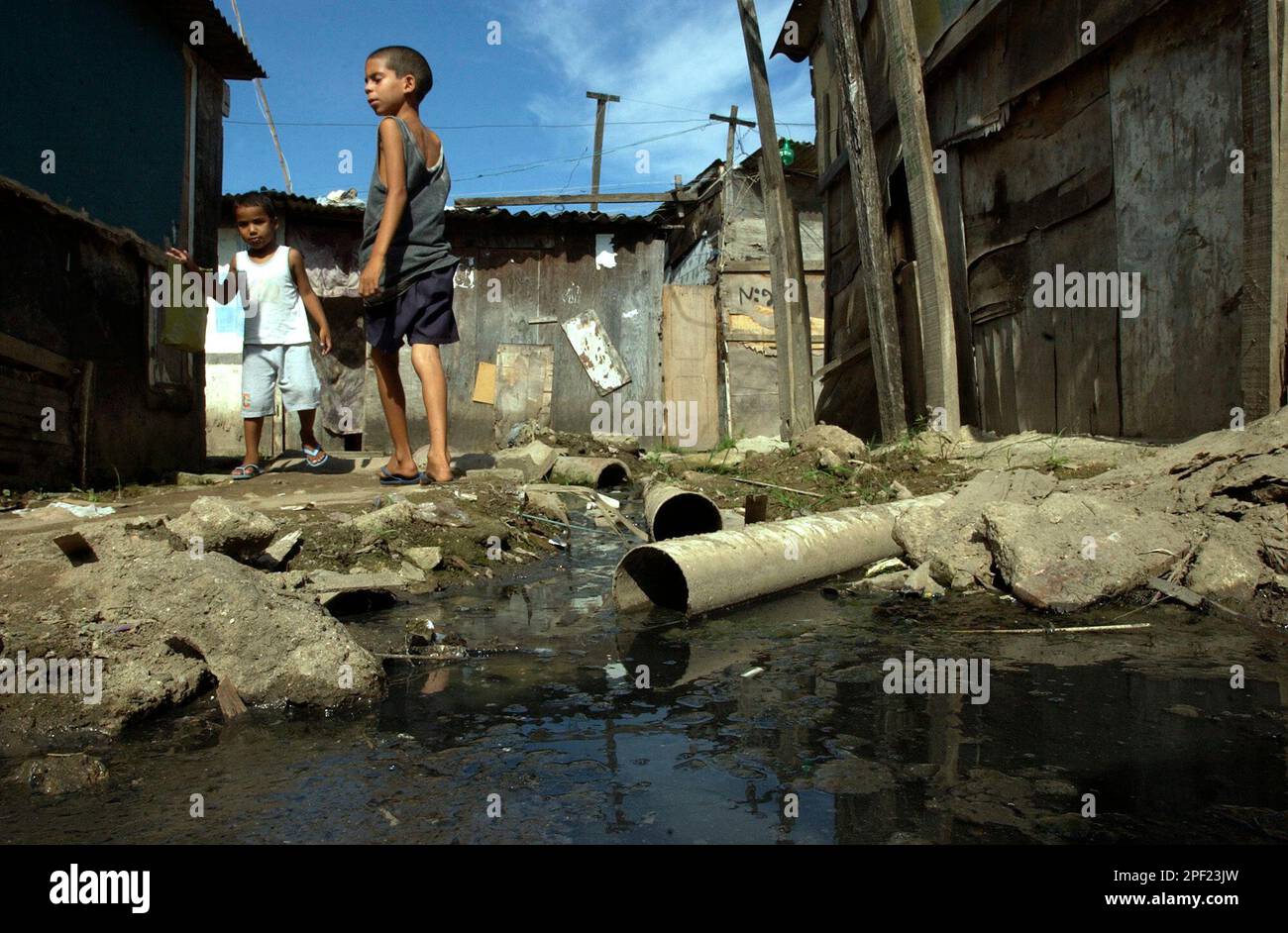 Children walk by a pool of raw sewage in Cidade de Deus (City of God ...