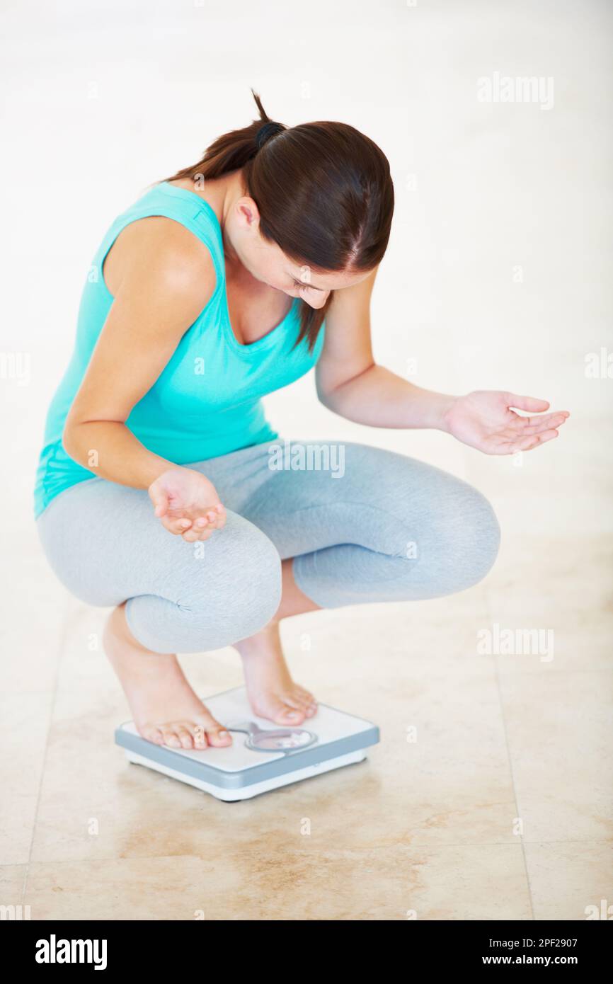 https://c8.alamy.com/comp/2PF2907/what-this-cant-be-righta-young-woman-looking-disbelievingly-at-the-scale-she-is-crouching-on-2PF2907.jpg
