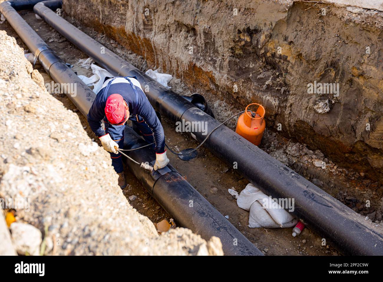 Rigger is gluing sheet of thermal protection on isolated pipeline using ...