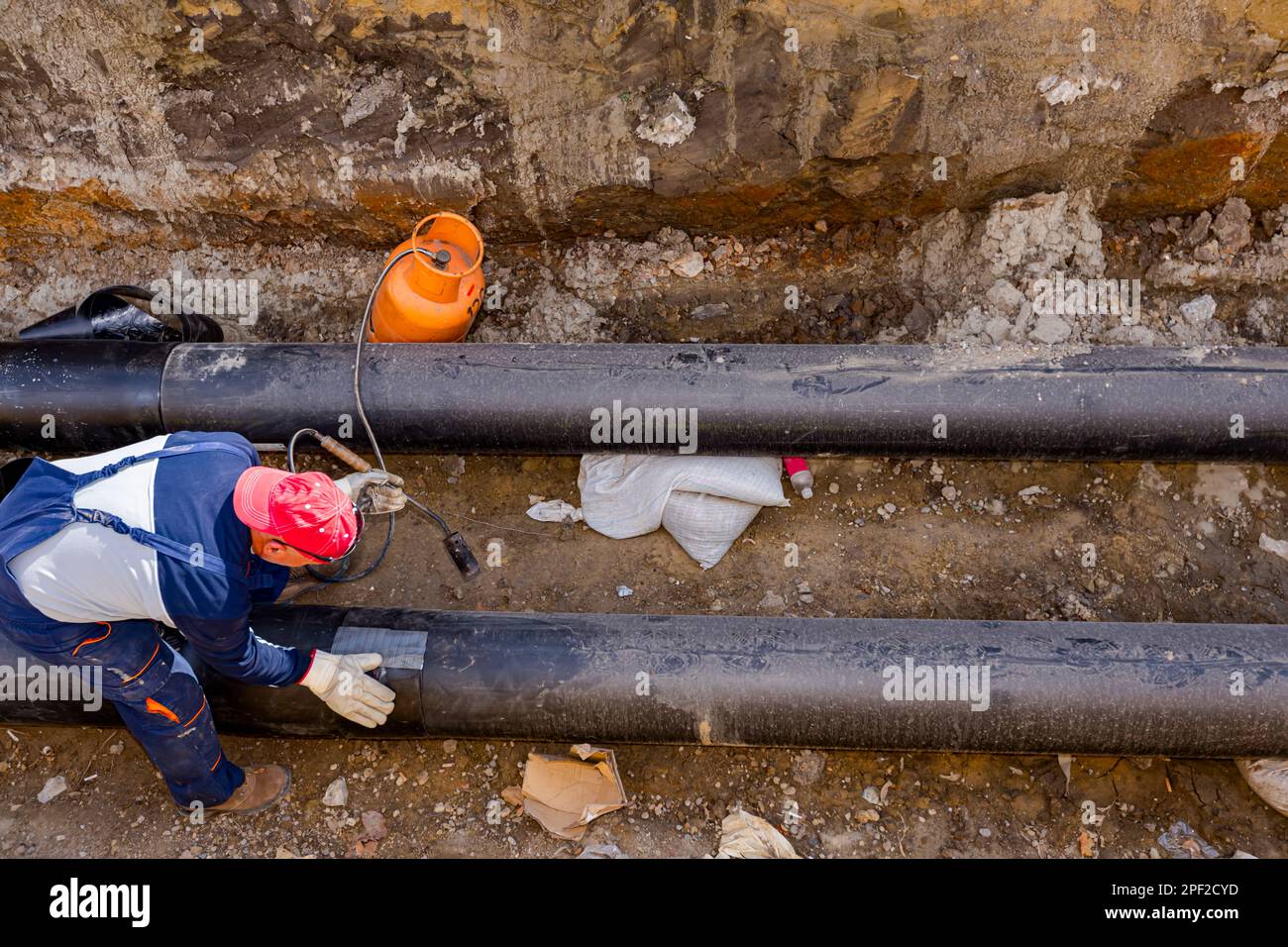 Rigger is gluing sheet of thermal protection on isolated pipeline using