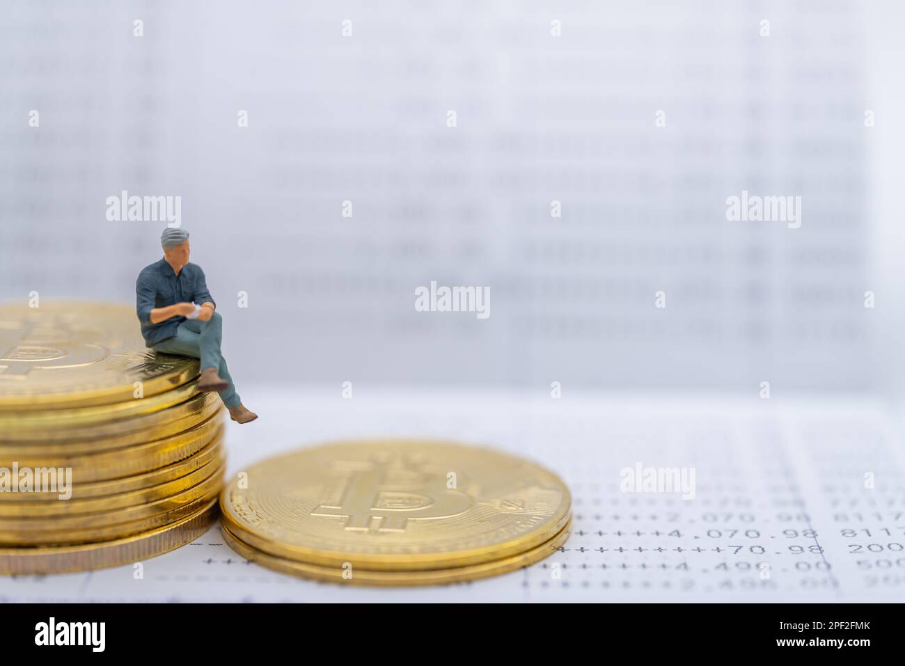 Business, Money, Cryptocurrency and Financial Concept. Businessman miniature figure sitting on stack of gold Bitcoin coins on bank passbook. Stock Photo