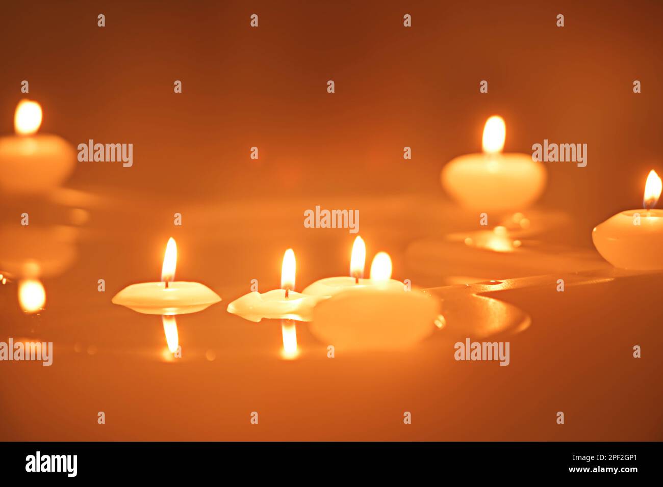 A number of small lighted candles floating in the water of a fountain