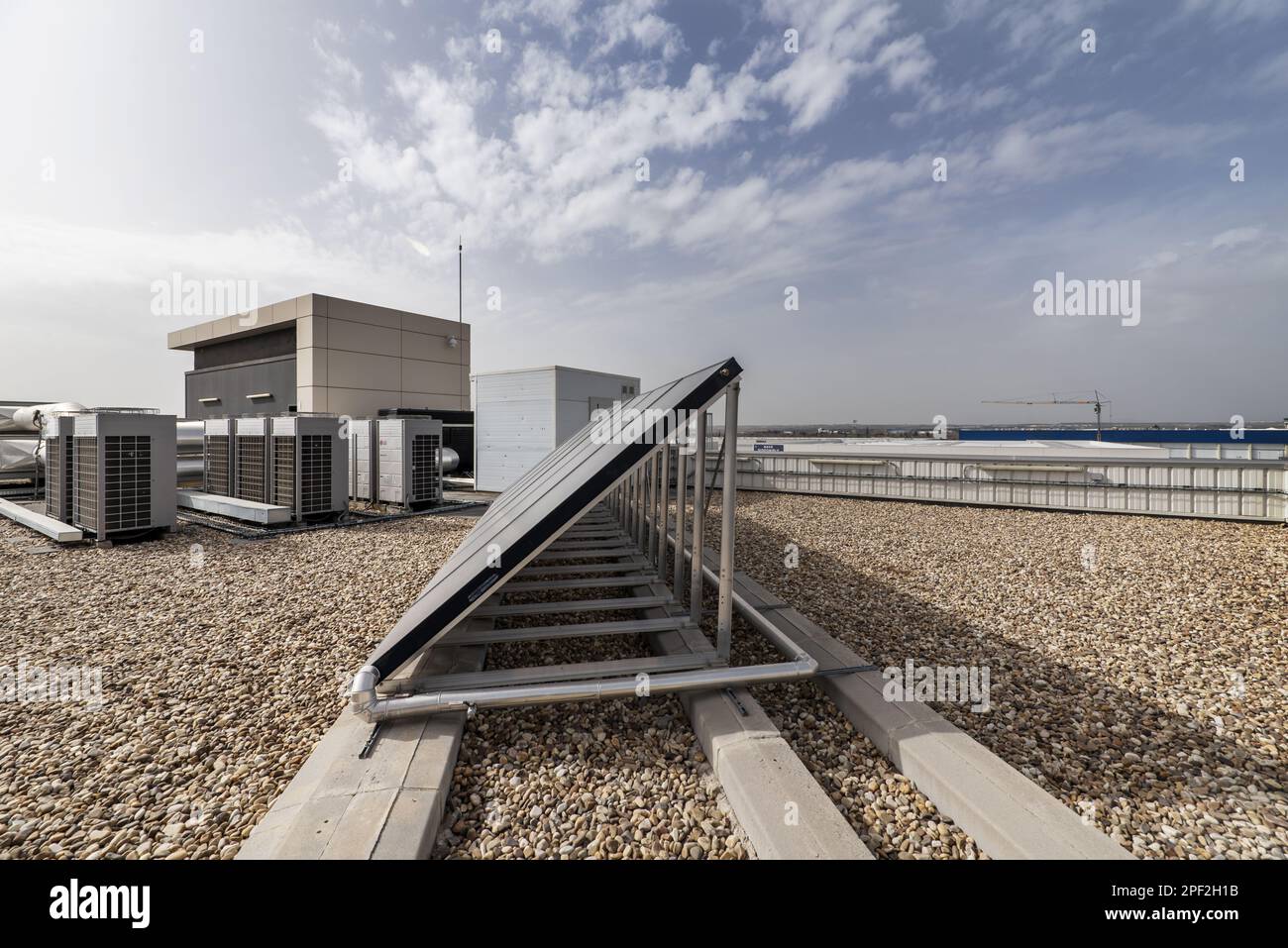 A solar panel to heat water on the roof of an industrial warehouse with gravel Stock Photo