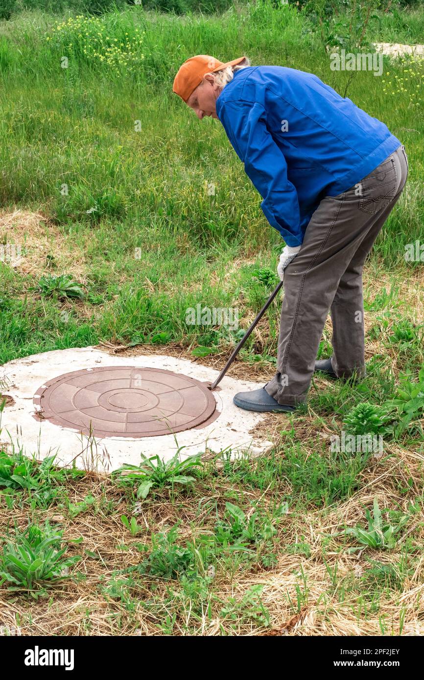 utility worker checks the water meter in the well by opening the well