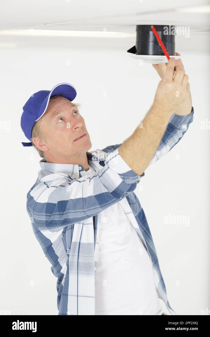 workman securing screws on ceiling vent Stock Photo
