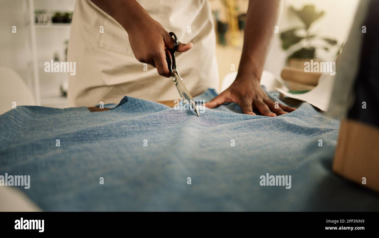 Creative designer cutting his fabric. Closeup of a tailor cutting denim