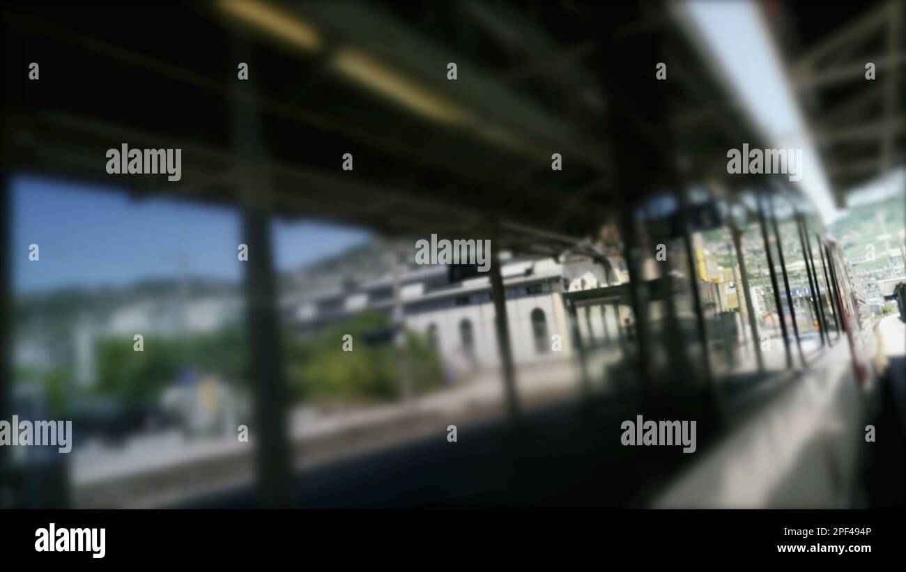 Moving train leaving platform station. Dutch angle of railroad wagon transportation departing Stock Photo