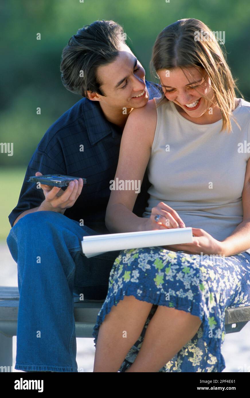 Romantic couple having fun sitting on a park bench Stock Photo