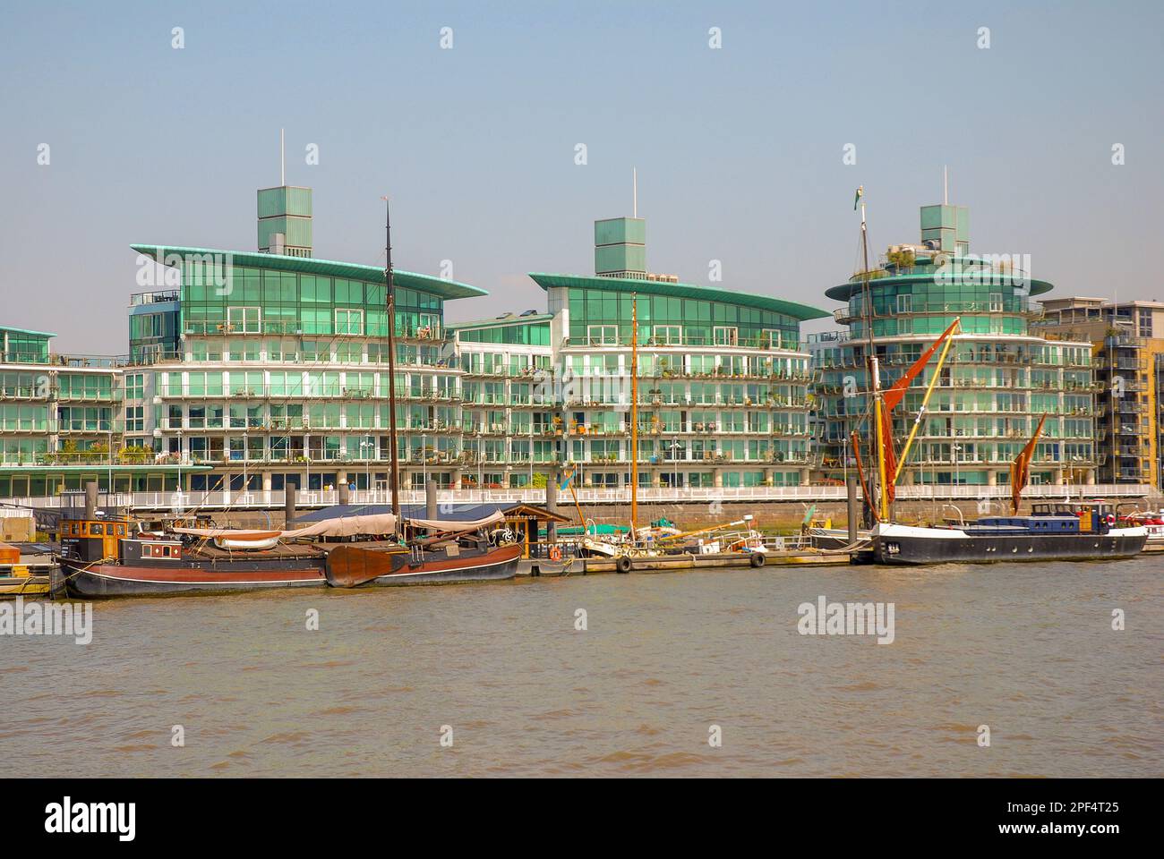 An estate with green modern residential buildings of original shape on the Thames River. There
