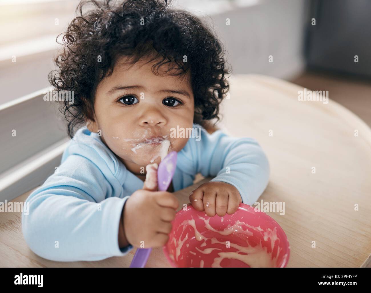 I dont like this flavour Mommy. an adorable little girl sitting alone in the kitchen and eating her breakfast. Stock Photo