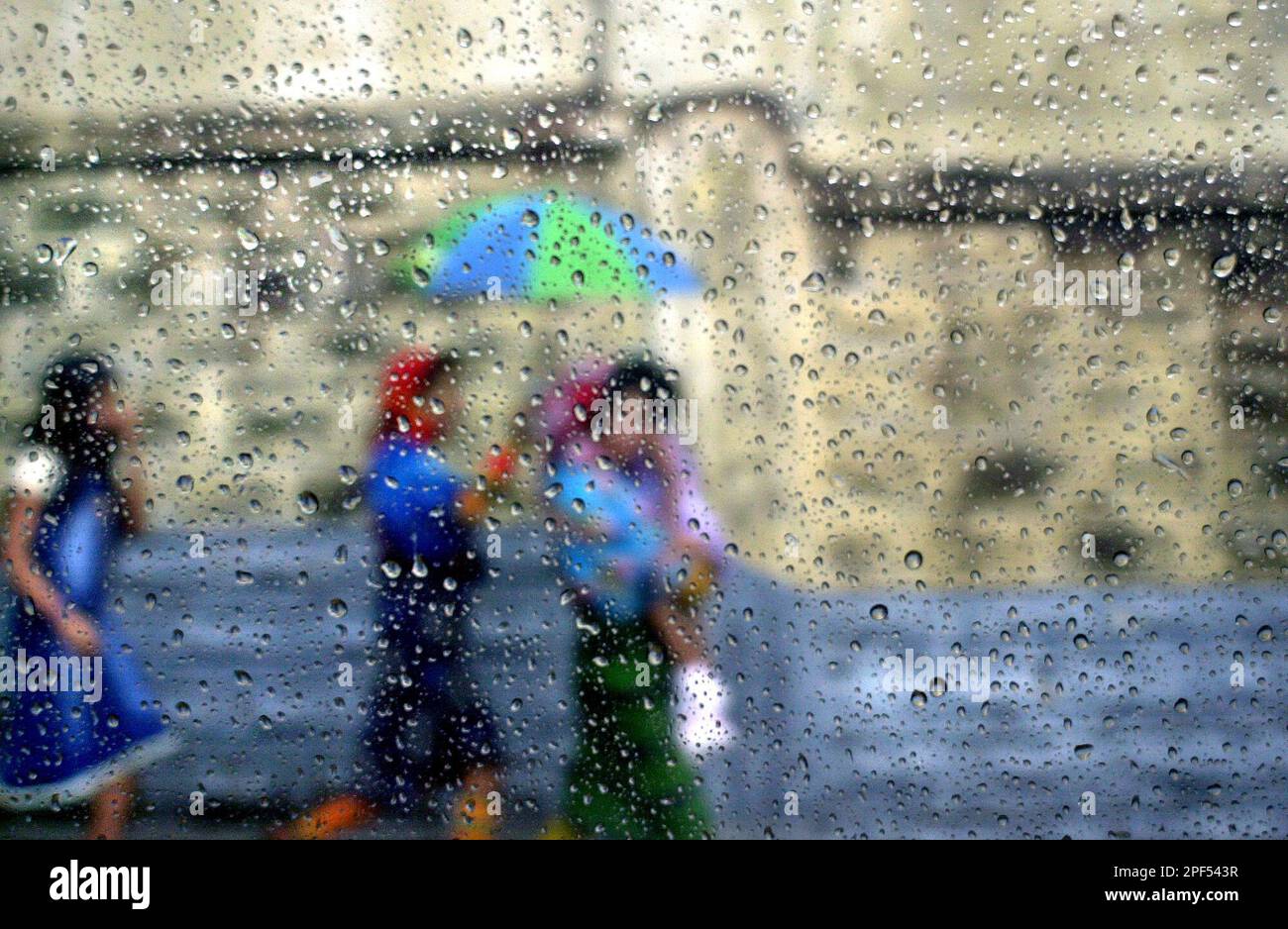 A group of women walk with an umbrella through a rain shower in Panama