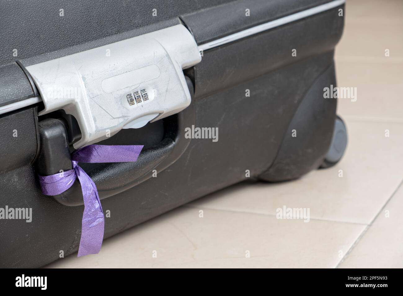Combination lock on an open suitcase baggage with a purple ribbon for