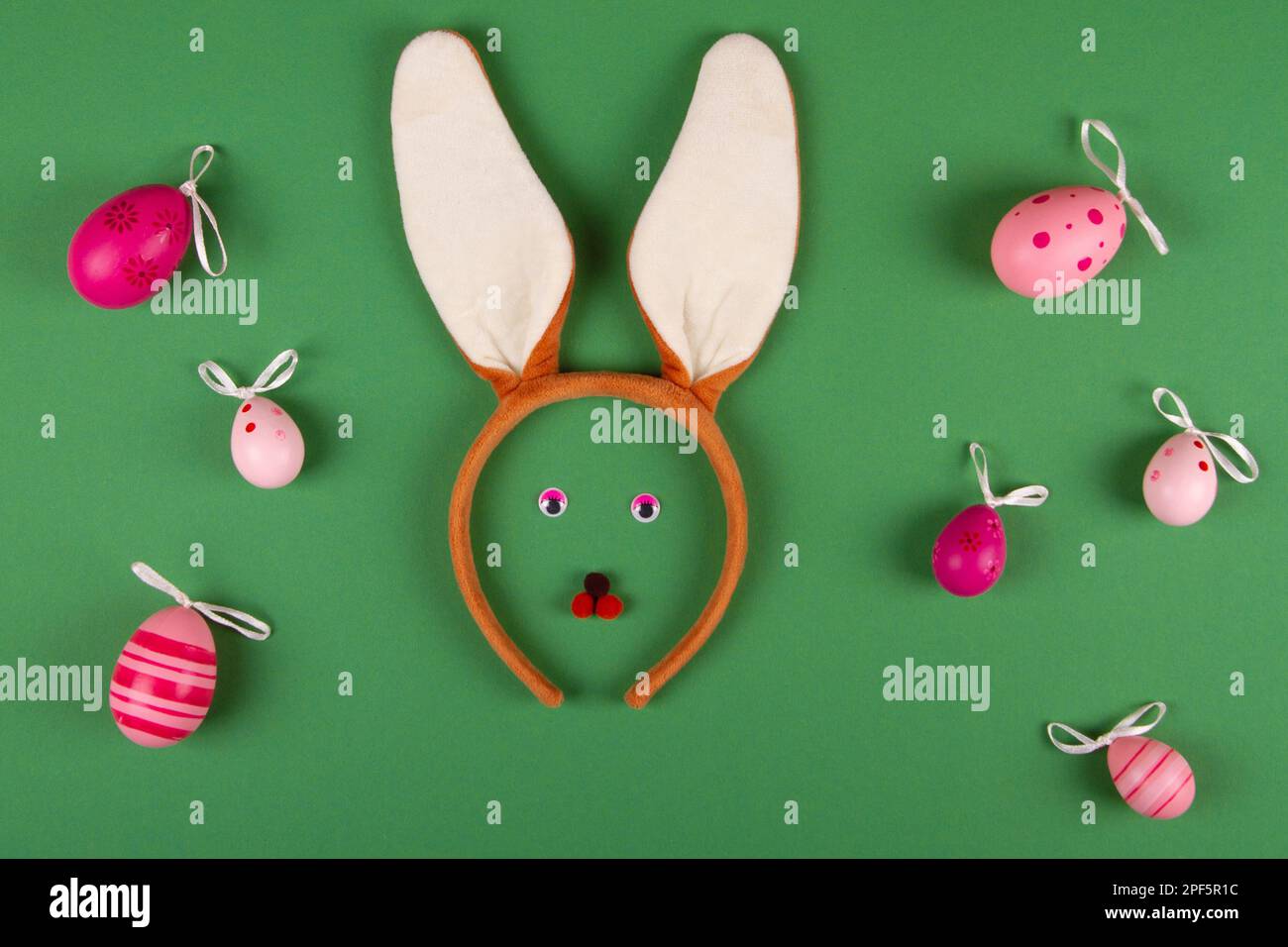 Funny easter green background with pink eggs and bunny face Stock Photo