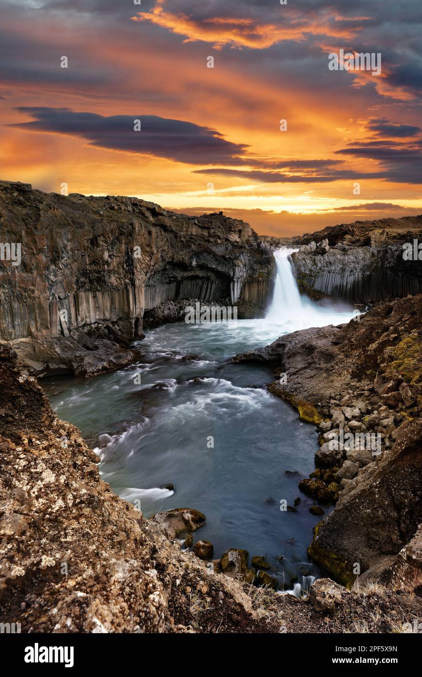 Iceland, waterfall with rapids in huge basalt rocks, above a contrasting evening sky with cloud formations with spectacular colours Stock Photo