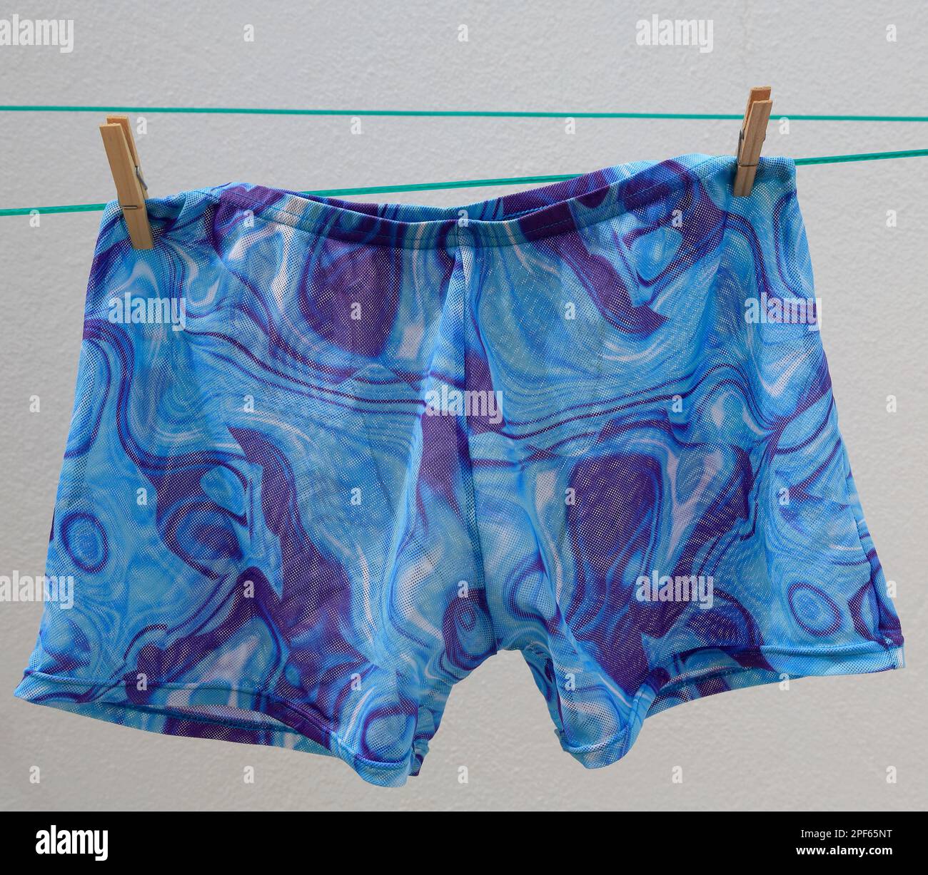 Swimming trunks on a washing line. Tan-through material. cym Stock Photo