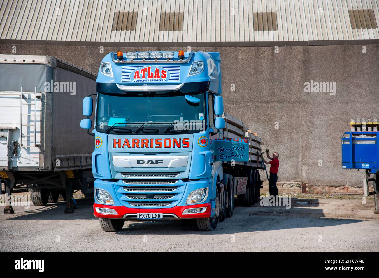 Truck driver tying down the load on a DAF truck pulling a flatbed