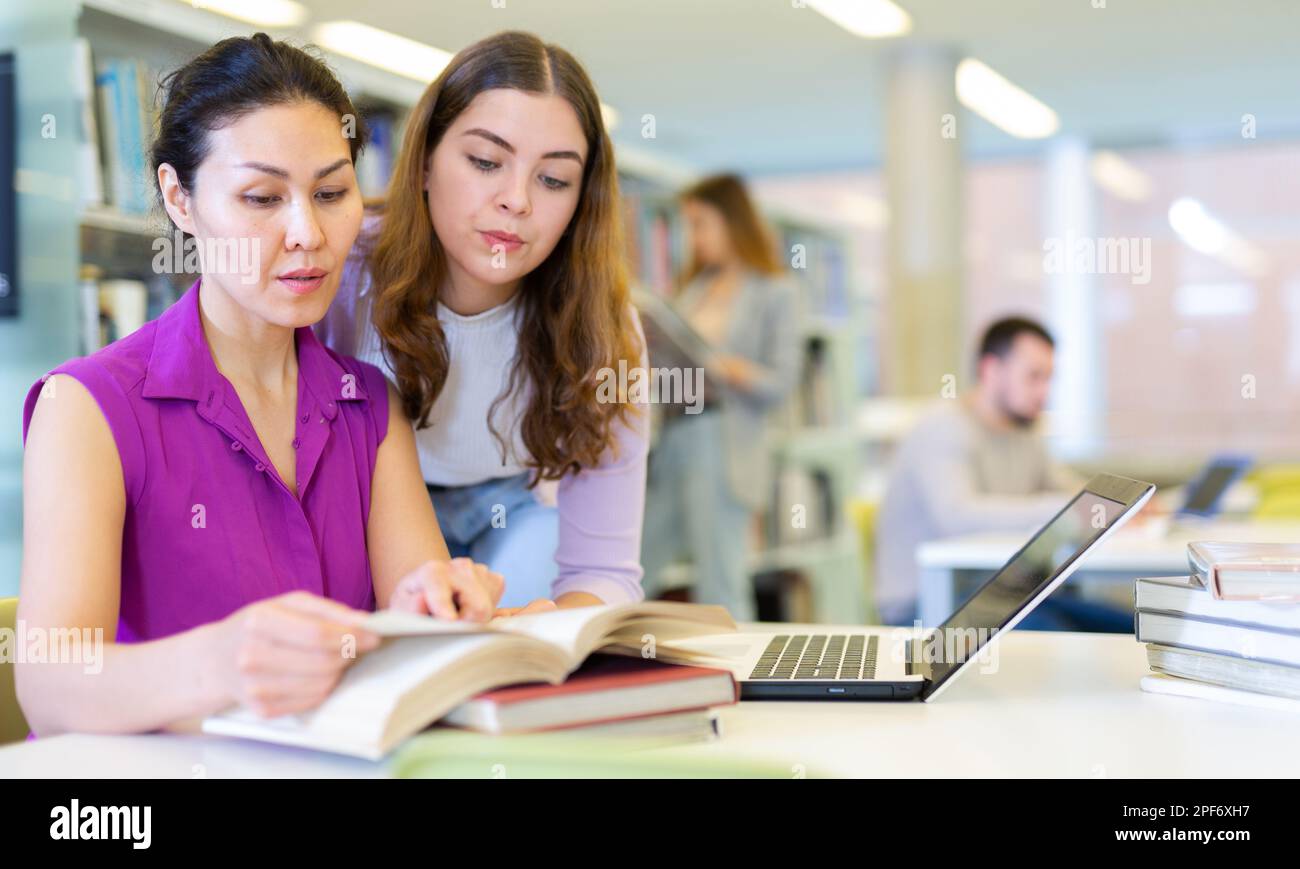 Two female colleagues working on joint project in library Stock Photo