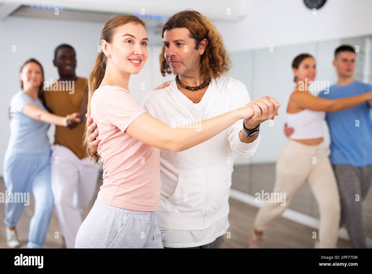 Group of diverse happy adult people dancing modern social dances in