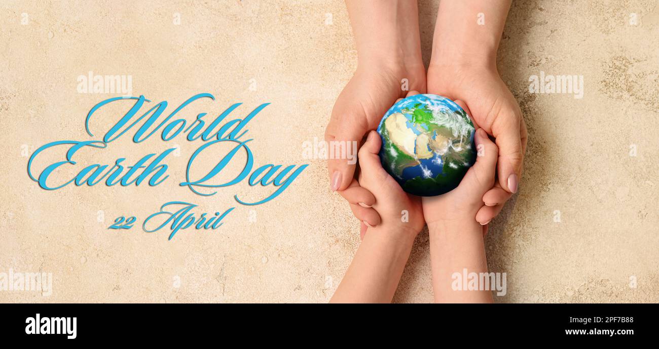 Hands of mother and child holding small planet on beige background ...