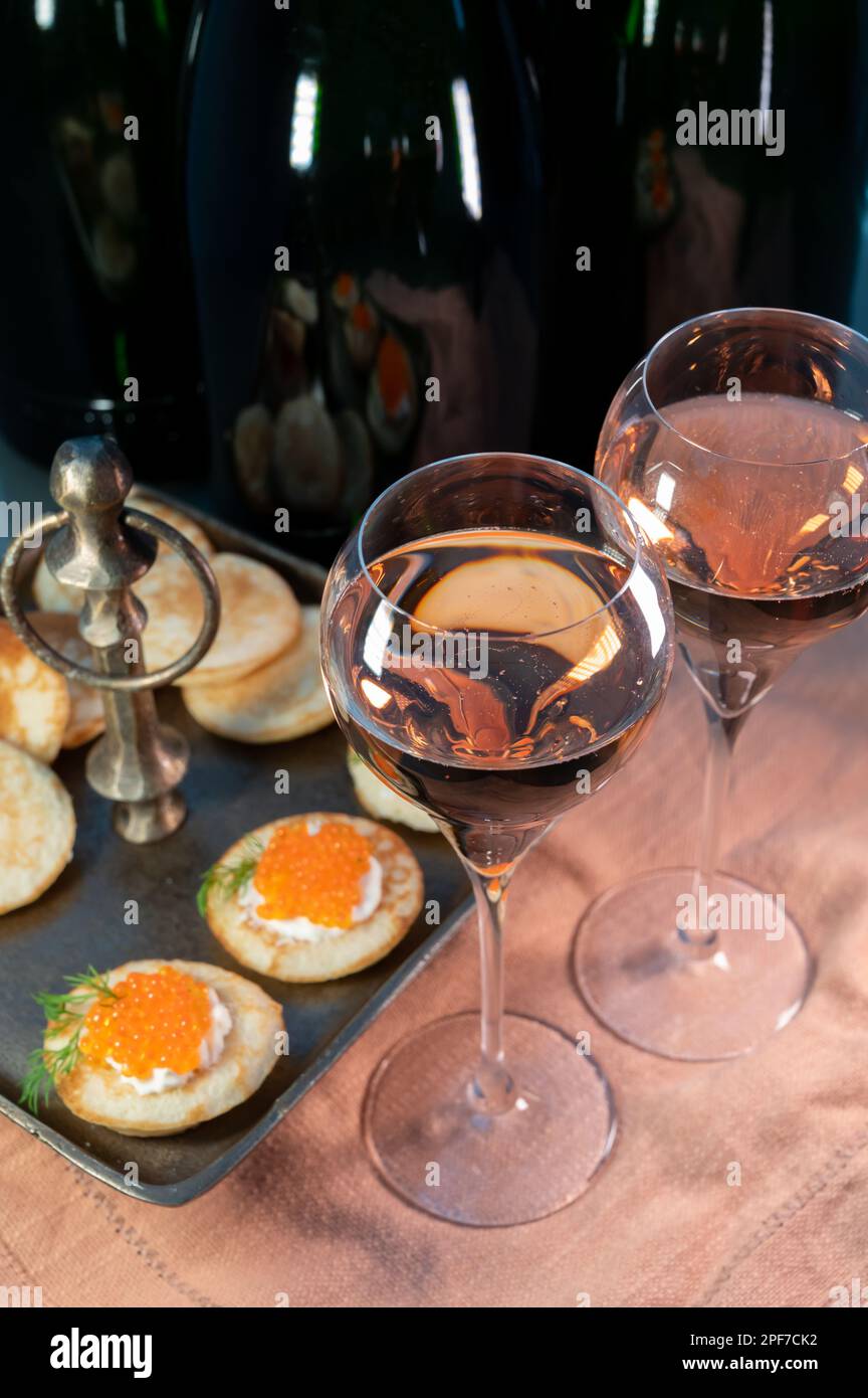 Tasting of rose Champagne sparkling wine with red caviar in cellars of