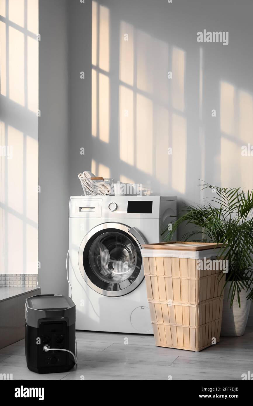 Washing machine plugged in portable power station in laundry room Stock