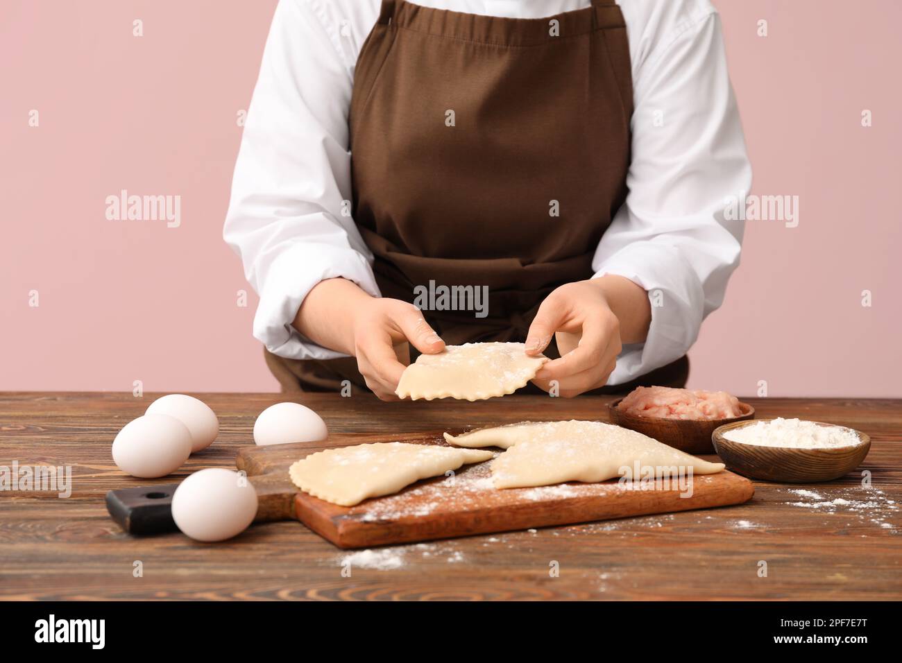 Woman preparing tasty meat empanadas at wooden table Stock Photo