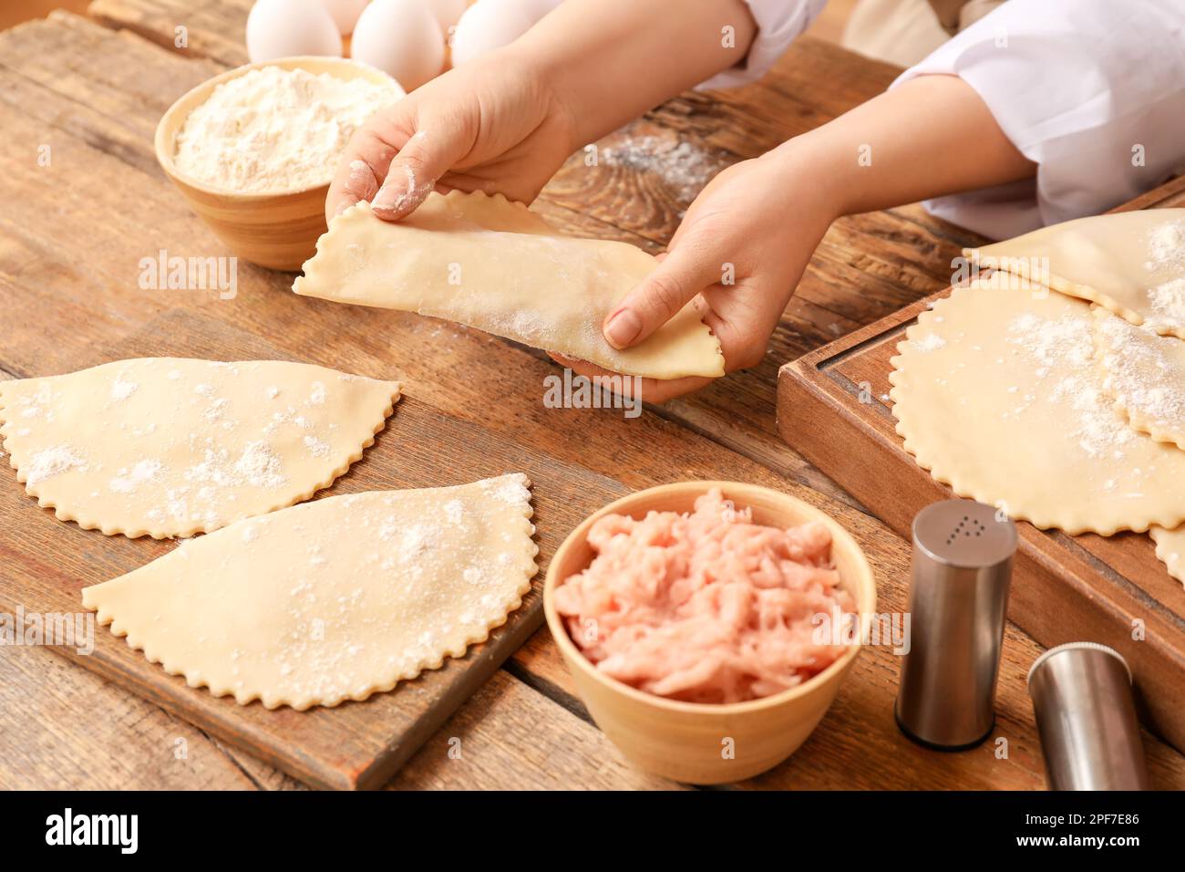 Woman with raw empanadas and forcemeat at wooden table Stock Photo