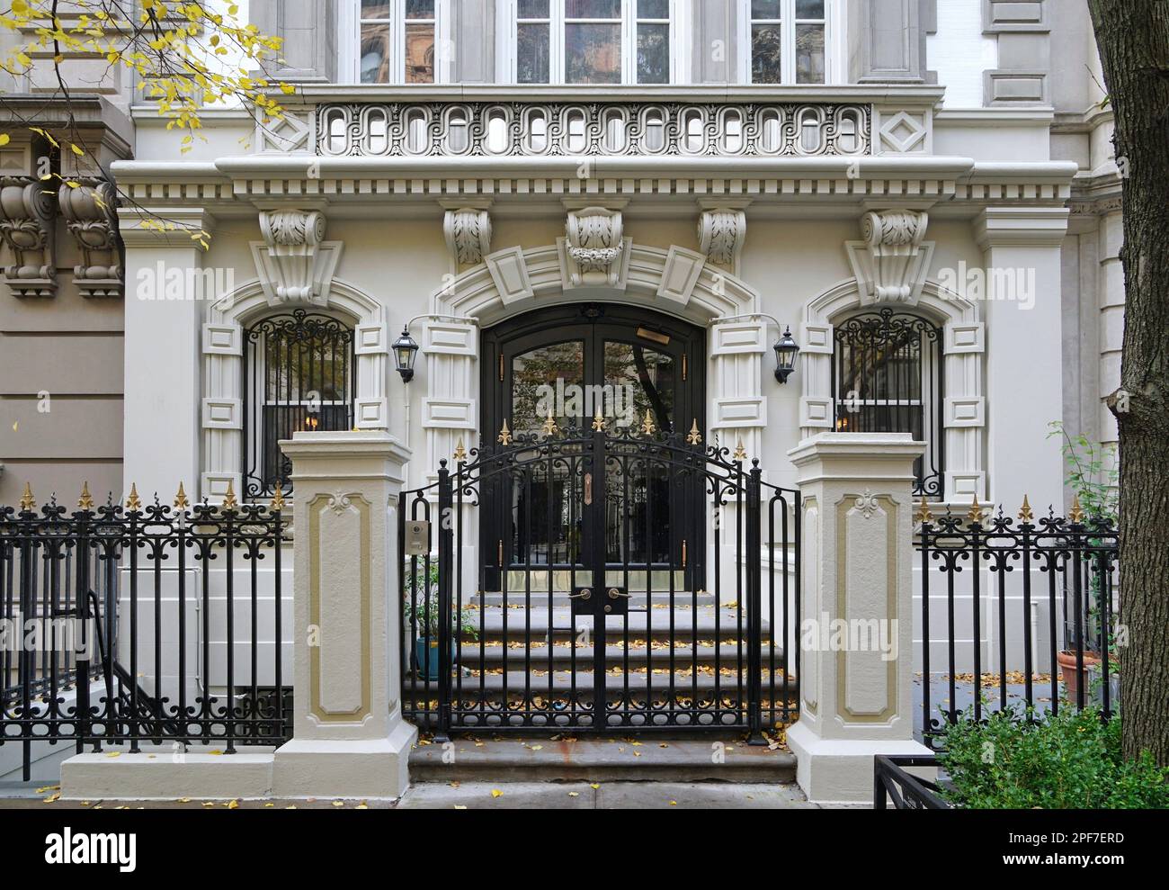 Front of elegant New York townhouse enclosed by fence and gate Stock