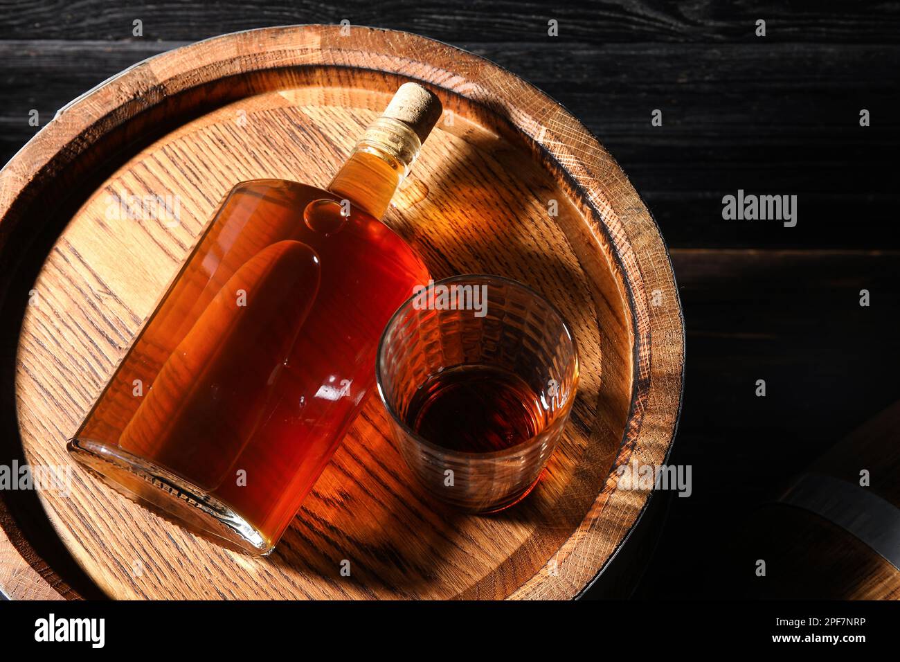 Oak barrel with glass and bottle of tasty whiskey on dark wooden background Stock Photo