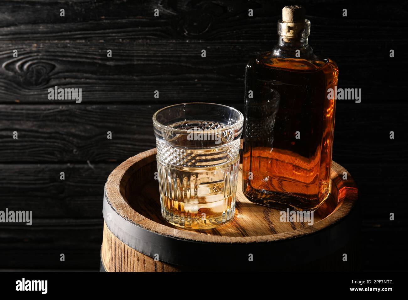 Oak barrel with bottle and glass of cold whiskey on dark wooden background Stock Photo