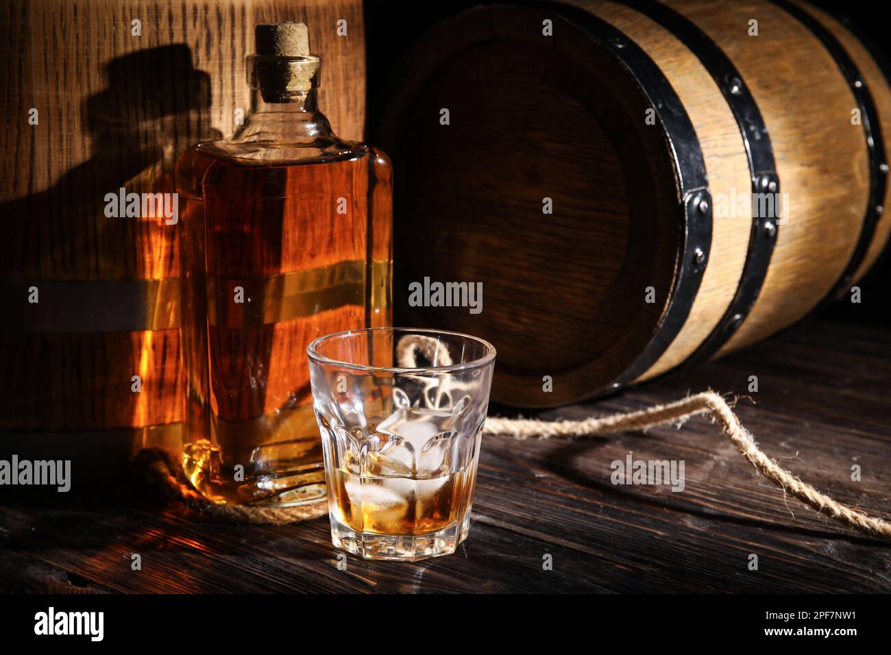 Oak barrels with bottle and glass of cold whiskey on dark wooden ...