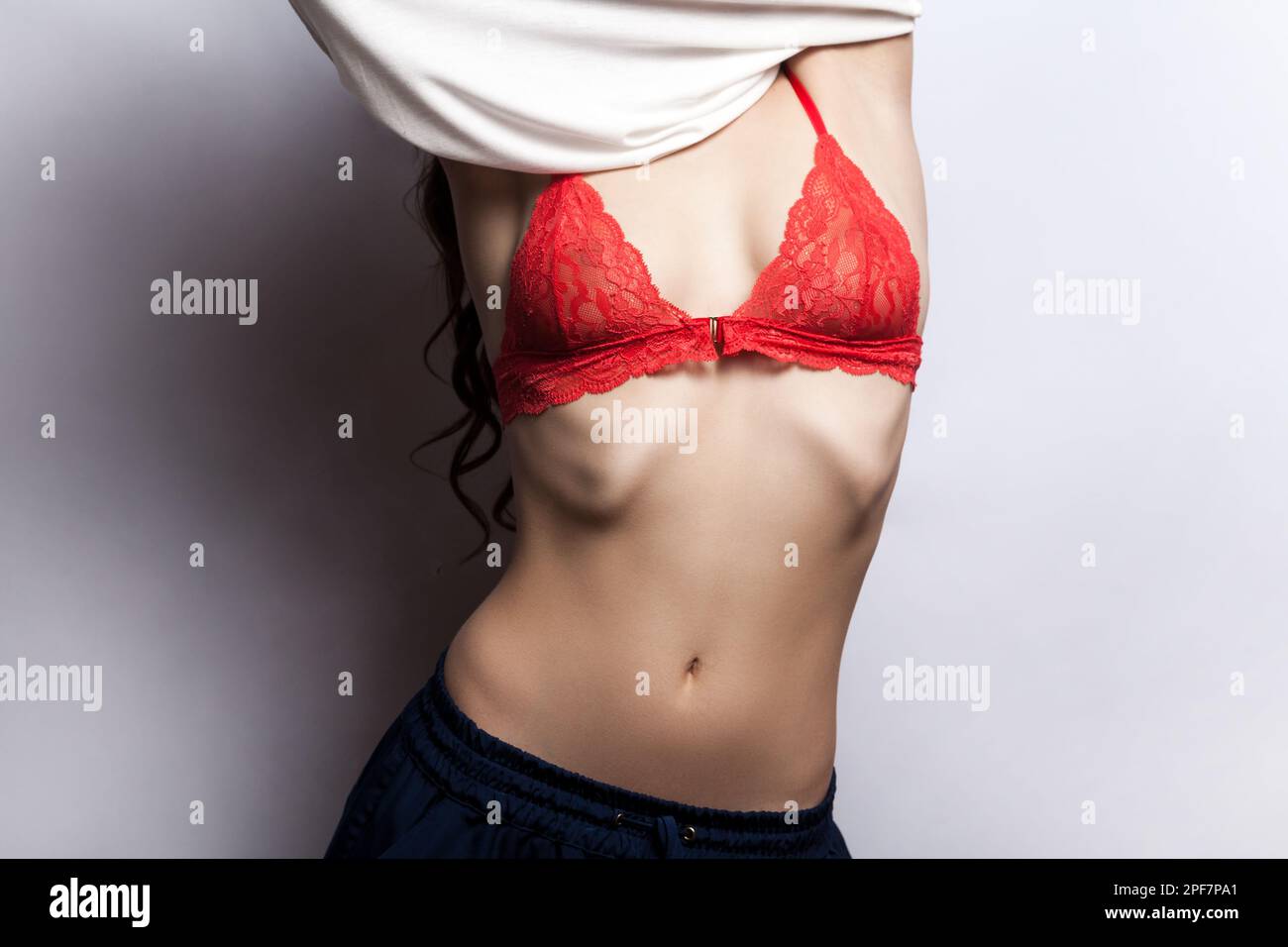 Portrait of unknown woman sensuality model taking off her shirt, showing  her beautiful perfect body and red sexy lingerie. Indoor shot isolated on  gray background Stock Photo - Alamy