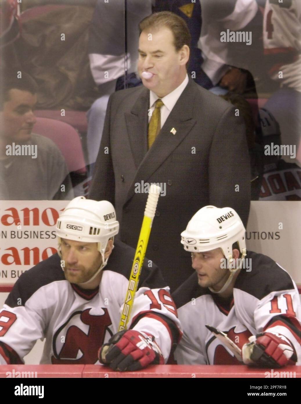 https://c8.alamy.com/comp/2PF7RY8/new-jersey-devils-coach-pat-burns-top-blows-a-bubble-as-he-and-players-jim-mckenzie-left-and-john-madden-watch-the-final-minute-of-their-3-0-shutout-over-the-boston-bruins-in-game-5-of-a-first-round-playoff-series-thursday-april-17-2003-in-east-rutherford-nj-the-devils-won-the-series-four-games-to-one-ap-photodaniel-hulshizer-2PF7RY8.jpg